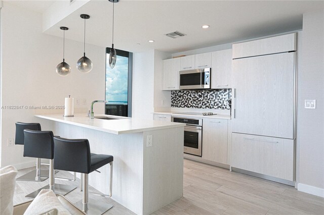 45 SW 9th St Unit 3403, Miami, FL 33130 - kitchen featuring stainless steel appliances, a peninsula, tasteful backsplash, a kitchen breakfast bar, and light wood-style floors
