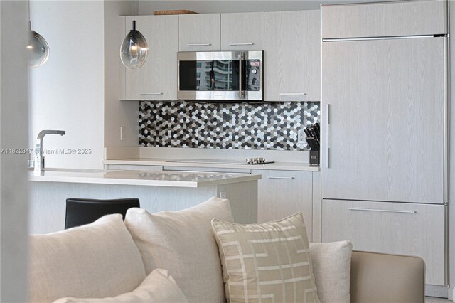 45 SW 9th St Unit 3403, Miami, FL 33130 - kitchen with stainless steel microwave, paneled refrigerator, light countertops, and backsplash