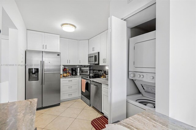 3731 N Country Club Dr Unit 2023, Aventura, FL 33180 - kitchen with appliances with stainless steel finishes, stacked washer / dryer, light tile patterned floors, white cabinets, and decorative backsplash