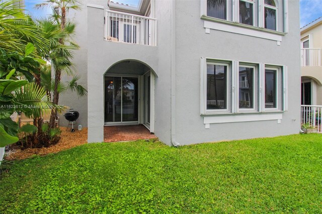 21025 NE 31st Ave, Aventura, FL 33180 - doorway to property with a balcony, stucco siding, and a lawn