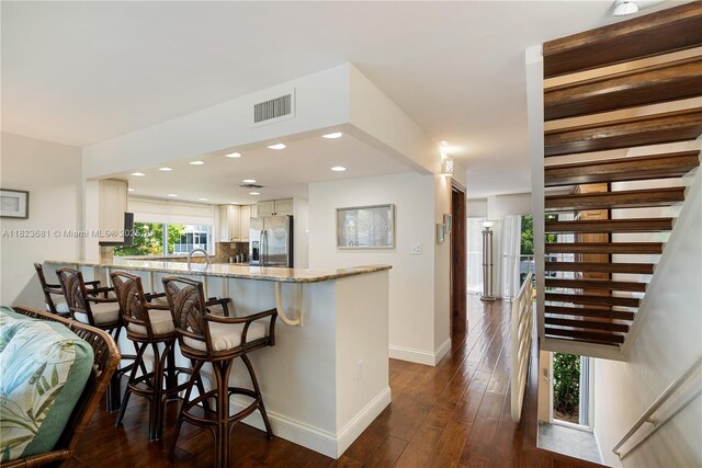 95 Coco Plum Dr Unit 1A, Marathon, FL 33050 - kitchen with stainless steel fridge with ice dispenser, light stone counters, a peninsula, dark wood-style flooring, and white cabinets