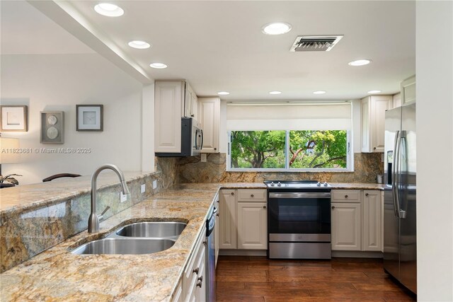 95 Coco Plum Dr Unit 1A, Marathon, FL 33050 - kitchen featuring stainless steel appliances, light stone counters, decorative backsplash, white cabinets, and recessed lighting