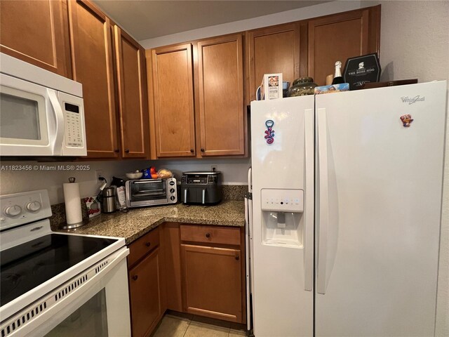 14745 SW 9th St Unit 3109, Pembroke Pines, FL 33027 - kitchen featuring white appliances, brown cabinets, dark countertops, and light tile patterned floors