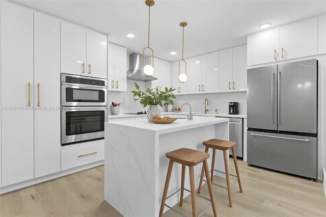 5401 Fillmore St, Hollywood, FL 33021 - kitchen with stainless steel appliances, wall chimney exhaust hood, light wood-style floors, light countertops, and white cabinetry