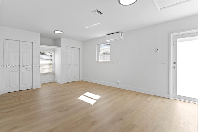 5401 Fillmore St, Hollywood, FL 33021 - unfurnished bedroom featuring a wall unit AC, two closets, and light wood-style flooring
