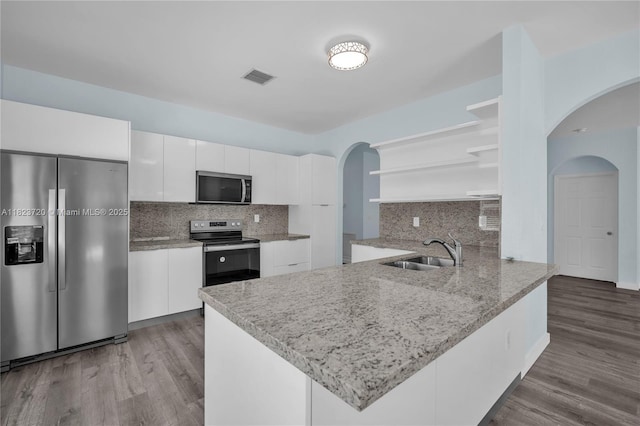 15452 SW 138th Ter, Miami, FL 33196 - kitchen with open shelves, stainless steel appliances, arched walkways, a peninsula, and white cabinets