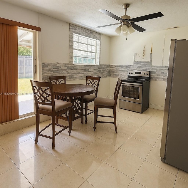 5348 W 14th Ave, Hialeah, FL 33012 - dining area featuring plenty of natural light, ceiling fan, wainscoting, and light tile patterned flooring