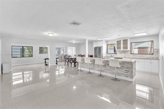 2035 SW 15th Ct, Deerfield Beach, FL 33442 - kitchen featuring freestanding refrigerator, a breakfast bar area, decorative backsplash, white cabinetry, and a kitchen island