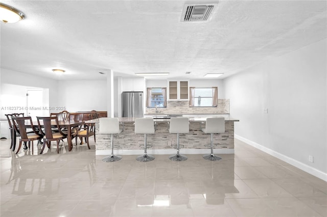 2035 SW 15th Ct, Deerfield Beach, FL 33442 - kitchen with freestanding refrigerator, a center island, a kitchen breakfast bar, decorative backsplash, and white cabinets