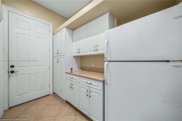 3859 Enchanted Oaks Ln, Sebring, FL 33875 - kitchen featuring freestanding refrigerator, white cabinets, light countertops, and light tile patterned floors