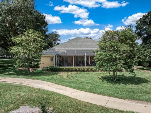 3859 Enchanted Oaks Ln, Sebring, FL 33875 - view of front facade featuring a front lawn, a tiled roof, and glass enclosure