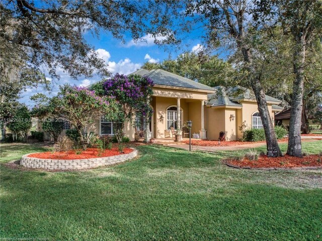 3859 Enchanted Oaks Ln, Sebring, FL 33875 - mediterranean / spanish house featuring stucco siding, a front lawn, and a tile roof