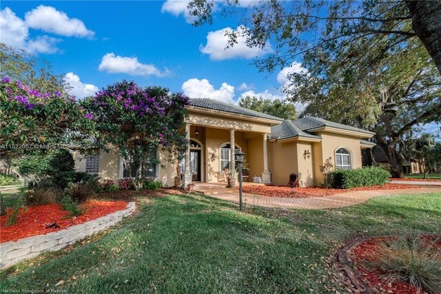 3859 Enchanted Oaks Ln, Sebring, FL 33875 - mediterranean / spanish house with stucco siding, a front yard, and a tiled roof