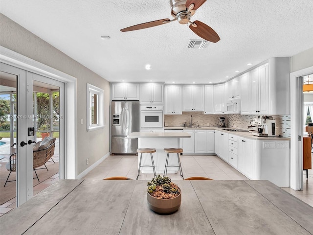 3920 NW 20th St, Coconut Creek, FL 33066 - kitchen with white appliances, plenty of natural light, ceiling fan, a center island, and a textured ceiling