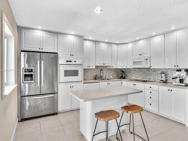 3920 NW 20th St, Coconut Creek, FL 33066 - kitchen with white appliances, light countertops, light tile patterned floors, backsplash, and white cabinets