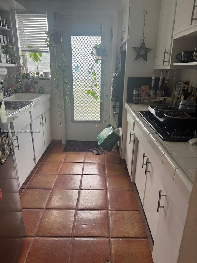 7921 E Dr Unit 8, North Bay Village, FL 33141 - kitchen with stovetop, tile countertops, white cabinetry, and open shelves