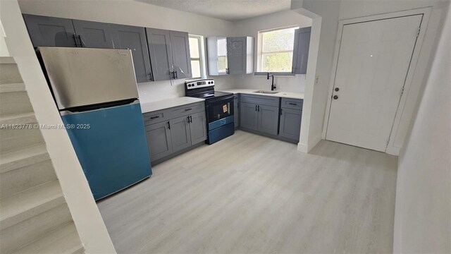 1000 W 28th St Unit 17, Hialeah, FL 33010 - kitchen featuring stainless steel range with electric cooktop, freestanding refrigerator, light countertops, light wood-style floors, and a textured ceiling