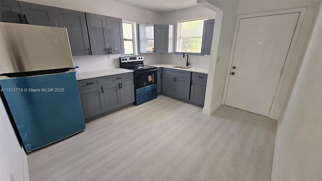 1000 W 28th St Unit 17, Hialeah, FL 33010 - kitchen with freestanding refrigerator, stainless steel range with electric cooktop, light wood-style flooring, gray cabinets, and light countertops