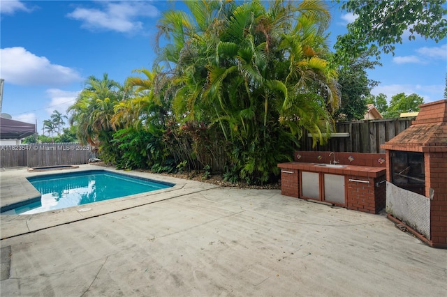 12540 SW 31st St, Miami, FL 33175 - view of swimming pool featuring a patio area, a fenced backyard, and an outdoor kitchen