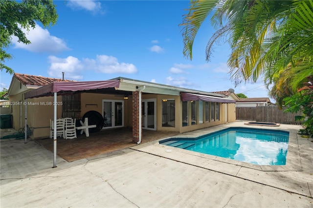 12540 SW 31st St, Miami, FL 33175 - view of swimming pool with french doors, an in-ground hot tub, a patio, and a fenced backyard