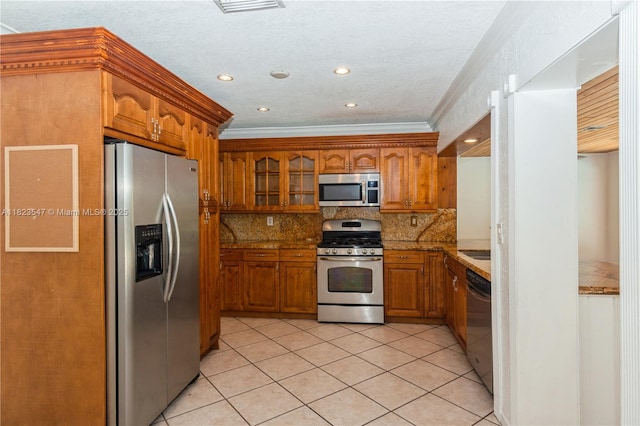 12540 SW 31st St, Miami, FL 33175 - kitchen featuring stainless steel appliances, brown cabinetry, light tile patterned floors, crown molding, and backsplash