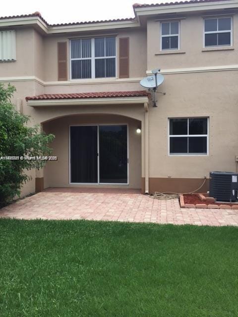 185 Riverwalk Cir, Sunrise, FL 33326 - rear view of house with stucco siding, a patio area, and a lawn