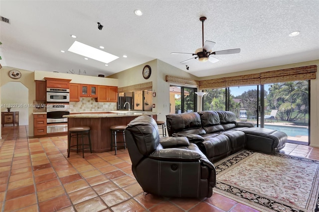 1180 NW 100th Way, Plantation, FL 33322 - living room featuring vaulted ceiling, a ceiling fan, a skylight, a textured ceiling, and recessed lighting