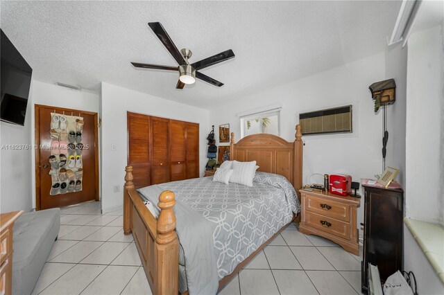 359 E 19th St, Hialeah, FL 33010 - bedroom featuring a closet, light tile patterned floors, a ceiling fan, a textured ceiling, and an AC wall unit