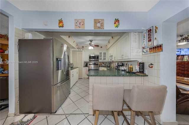 359 E 19th St, Hialeah, FL 33010 - kitchen featuring stainless steel appliances, a peninsula, dark countertops, ceiling fan, and light tile patterned floors