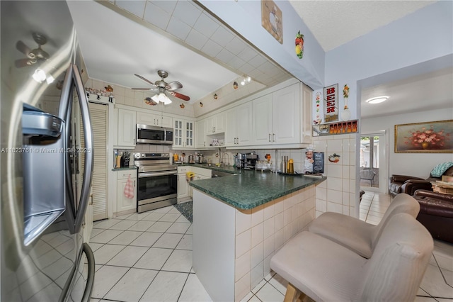 359 E 19th St, Hialeah, FL 33010 - kitchen featuring appliances with stainless steel finishes, a peninsula, light tile patterned floors, and dark countertops