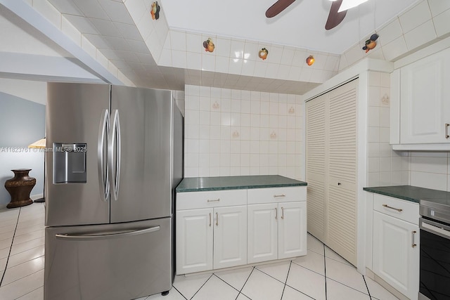 359 E 19th St, Hialeah, FL 33010 - kitchen featuring stainless steel fridge, dark countertops, white cabinetry, light tile patterned floors, and backsplash