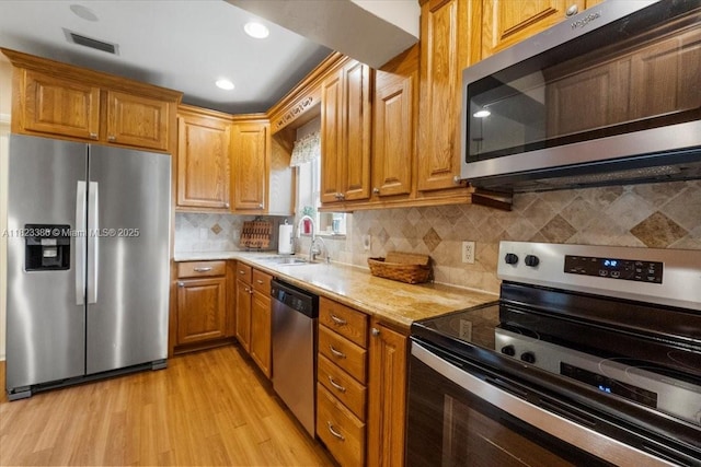 404 NE 11th Ave, Pompano Beach, FL 33060 - kitchen featuring stainless steel appliances, light wood finished floors, tasteful backsplash, brown cabinetry, and recessed lighting