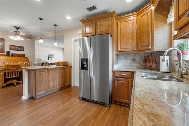 404 NE 11th Ave, Pompano Beach, FL 33060 - kitchen with stainless steel fridge with ice dispenser, light wood-style flooring, a peninsula, decorative backsplash, and brown cabinets