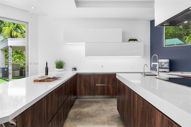 10620 SW 74th Ave, Pinecrest, FL 33156 - kitchen with modern cabinets, concrete floors, light countertops, wall chimney range hood, and dark brown cabinetry
