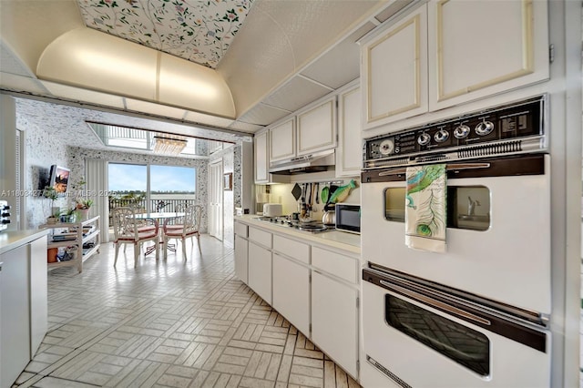 1800 NE 114th St Unit 604, Miami, FL 33181 - kitchen featuring double oven, brick patterned floors, gas cooktop, light countertops, and white cabinetry