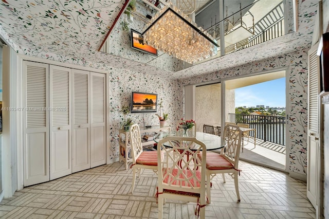 1800 NE 114th St Unit 604, Miami, FL 33181 - dining area featuring wallpapered walls, brick patterned floors, a chandelier, and a towering ceiling