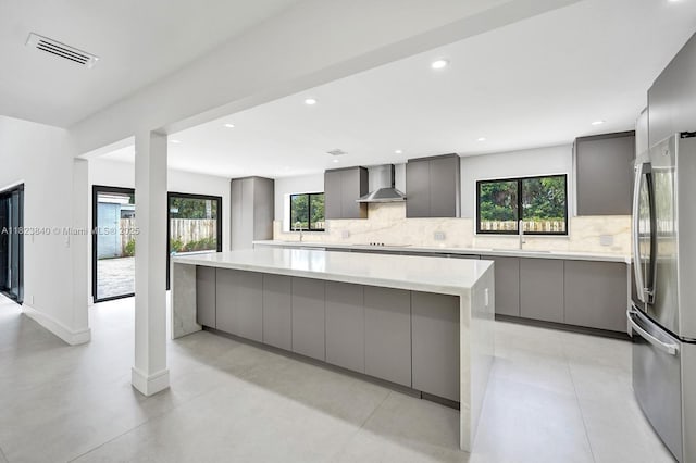 7340 Andorra Pl, Boca Raton, FL 33433 - kitchen featuring gray cabinetry, freestanding refrigerator, modern cabinets, wall chimney range hood, and tasteful backsplash
