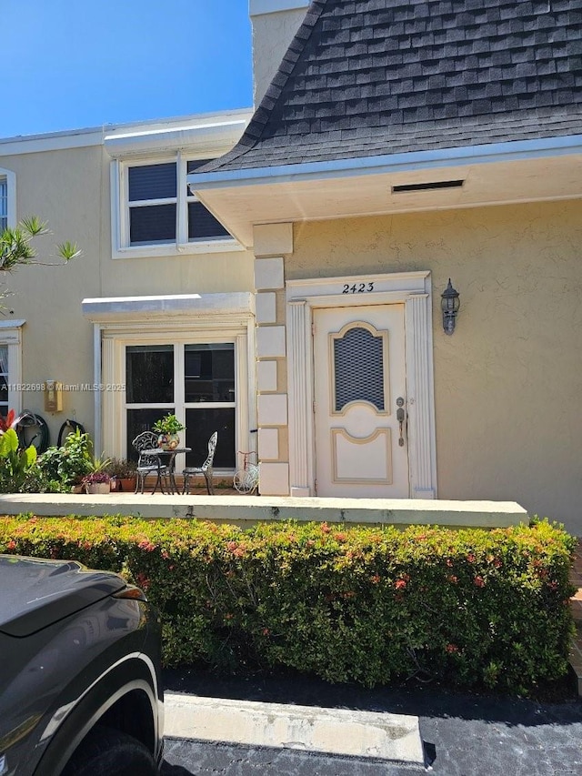 2423 NE 10th St Unit 154, Hallandale Beach, FL 33009 - doorway to property featuring roof with shingles and stucco siding