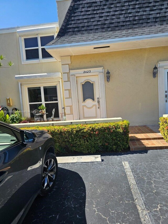 2423 NE 10th St Unit 154, Hallandale Beach, FL 33009 - view of exterior entry with a shingled roof, stucco siding, and uncovered parking