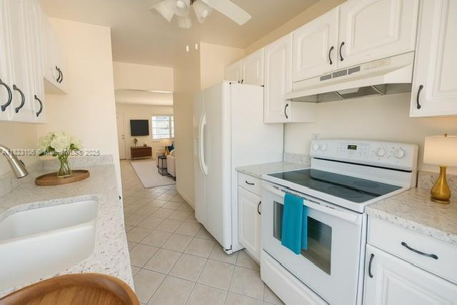3923 NE 166th St Unit N208, North Miami Beach, FL 33160 - kitchen with white appliances, under cabinet range hood, light tile patterned floors, white cabinets, and ceiling fan