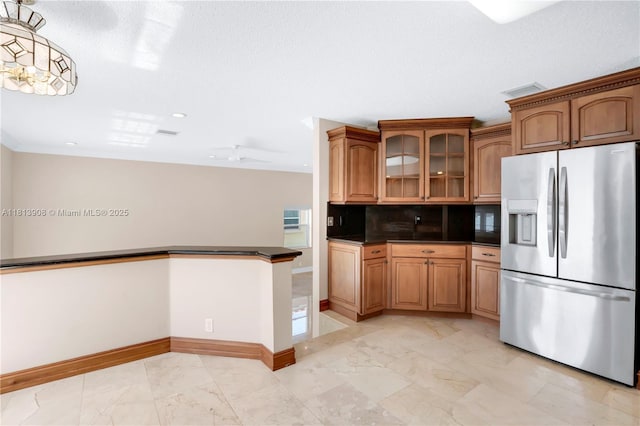 1020 NW 184th Ter, Pembroke Pines, FL 33029 - kitchen with stainless steel fridge with ice dispenser, light marble finish floors, dark countertops, brown cabinets, and glass insert cabinets
