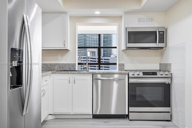 600 Parkview Dr Unit 624, Hallandale Beach, FL 33009 - kitchen featuring appliances with stainless steel finishes, white cabinetry, light stone countertops, recessed lighting, and light wood-type flooring