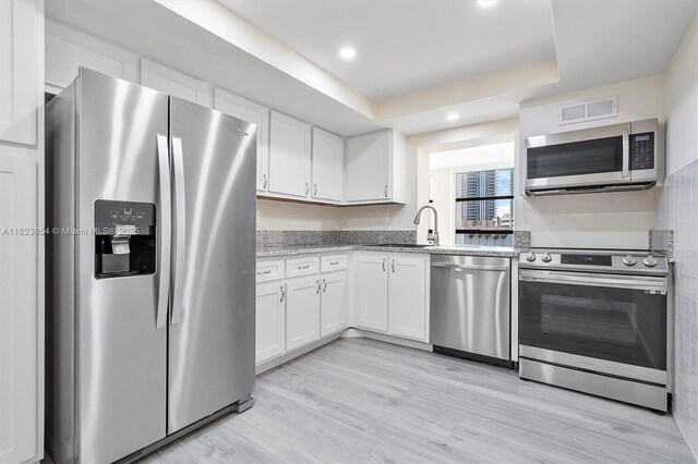 600 Parkview Dr Unit 624, Hallandale Beach, FL 33009 - kitchen featuring stainless steel appliances, white cabinetry, recessed lighting, a tray ceiling, and light wood finished floors
