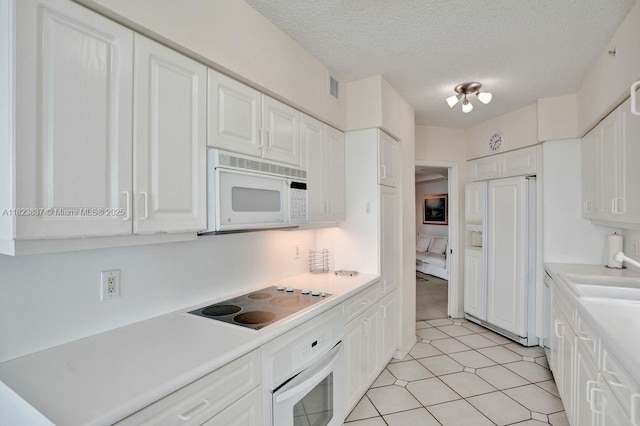 16400 Collins Ave Unit 544, Sunny Isles Beach, FL 33160 - kitchen featuring white appliances, white cabinetry, light countertops, a textured ceiling, and light tile patterned floors