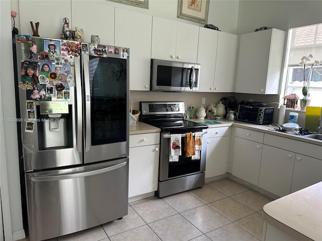 9860 SW 161st Ave, Miami, FL 33196 - kitchen featuring stainless steel appliances, light countertops, light tile patterned floors, and white cabinets