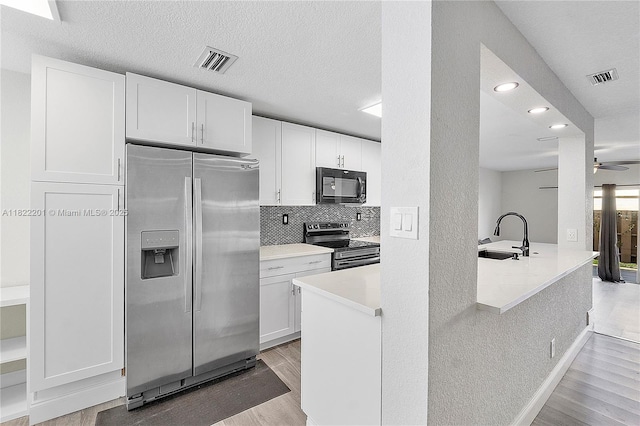 8239 NW 8th St Unit 3, Plantation, FL 33324 - kitchen with appliances with stainless steel finishes, light wood finished floors, white cabinetry, light countertops, and recessed lighting