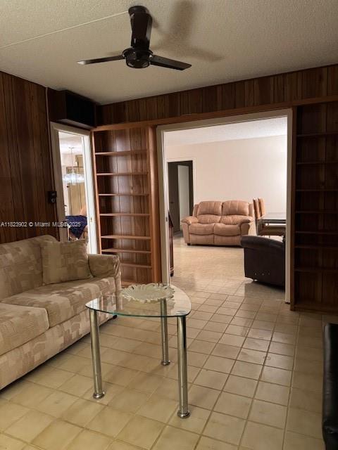 13648 Coconut Palm Ct Unit C, Delray Beach, FL 33484 - living area with wood walls, ceiling fan, a textured ceiling, light tile patterned floors, and built in shelves