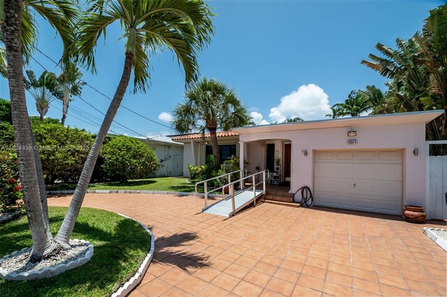 9064 Garland Ave, Surfside, FL 33154 - view of front of property featuring a garage, stucco siding, and a front lawn