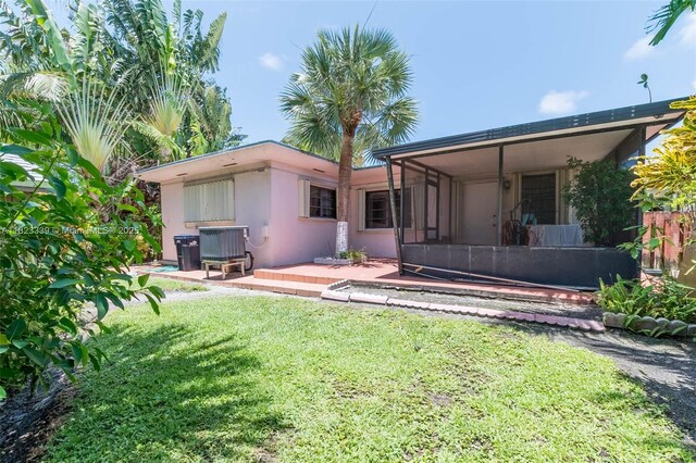 9064 Garland Ave, Surfside, FL 33154 - rear view of house with stucco siding, a yard, a sunroom, and a wooden deck