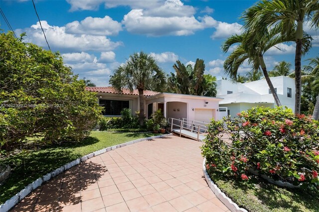 9064 Garland Ave, Surfside, FL 33154 - view of front facade with an attached garage, driveway, stucco siding, and a tile roof